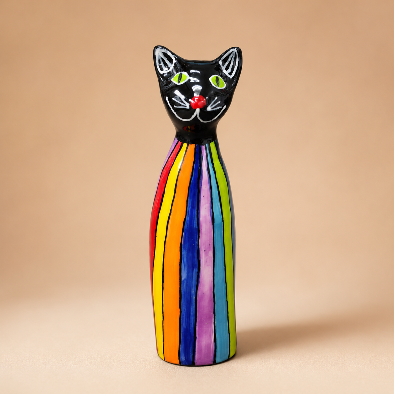 Handcrafted Rainbow Striped Ceramic Cat Figurine photographed on a warm beige studio background