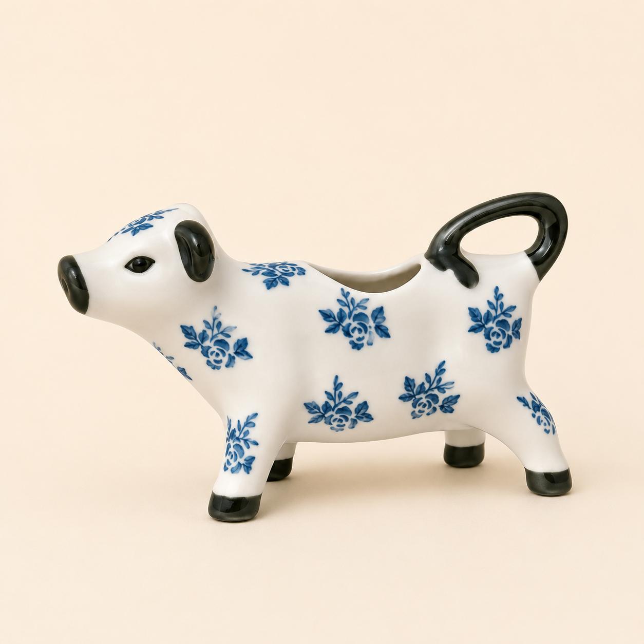 Blue and White Floral Cow Creamer Jug photographed on a warm beige studio background