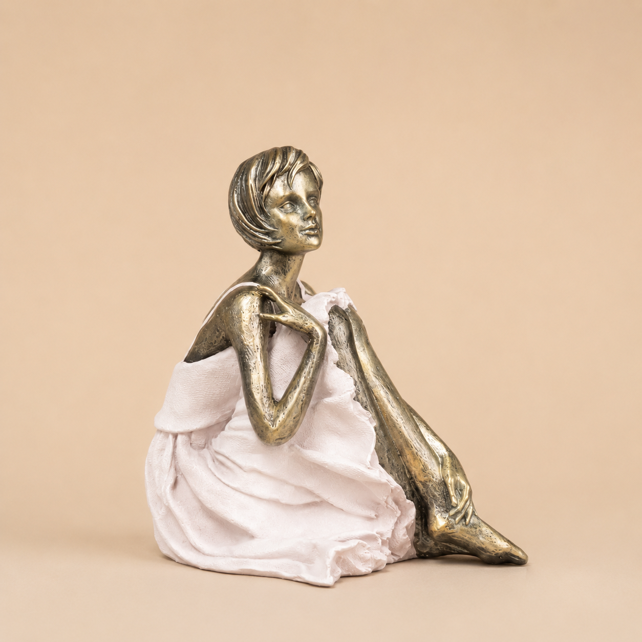 Gold and White Seated Woman Figurine photographed on a warm beige studio background