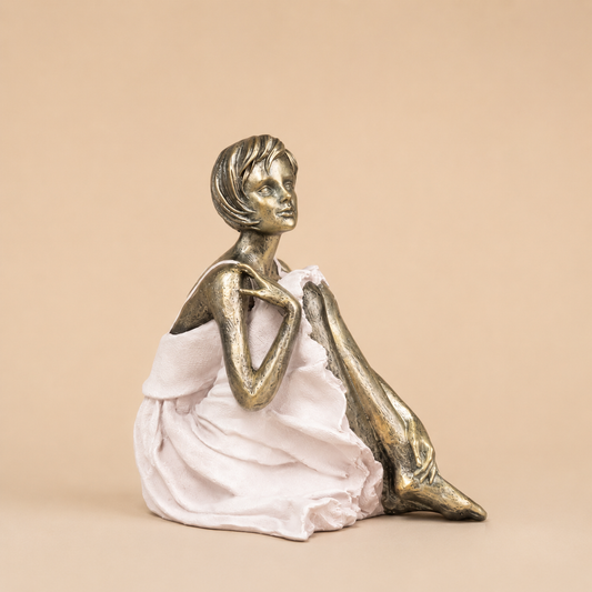 Gold and White Seated Woman Figurine photographed on a warm beige studio background