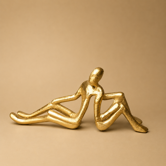 Gold Reclining Couple Sculpture photographed on a warm beige studio background